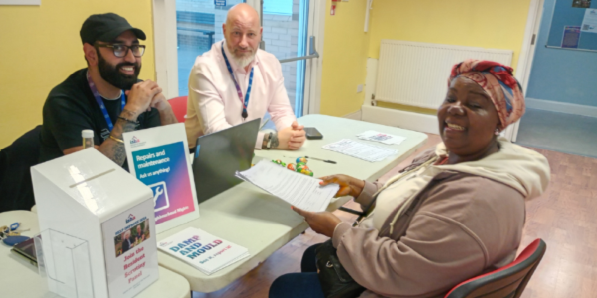 A resident is sitting at a table across from members of our repairs team giving her feedback